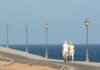 Senior couple walking on a seaside promenade enjoying a peaceful day by the ocean.