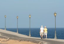 Senior couple walking on a seaside promenade enjoying a peaceful day by the ocean.