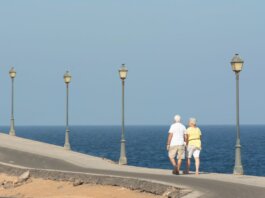 Senior couple walking on a seaside promenade enjoying a peaceful day by the ocean.