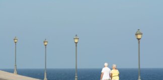 Senior couple walking on a seaside promenade enjoying a peaceful day by the ocean.