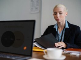 Serious young woman in formal clothes sitting at table and working with documents in office