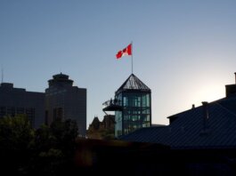 Silhouette of Winnipeg skyline with Canadian flag during sunset, showcasing modern architecture.