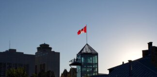 Silhouette of Winnipeg skyline with Canadian flag during sunset, showcasing modern architecture.
