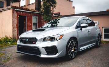 Subaru стала партнёром чемпионата по триатлону в Виктории Silver Subaru WRX STI parked in a residential driveway with rustic backdrop.