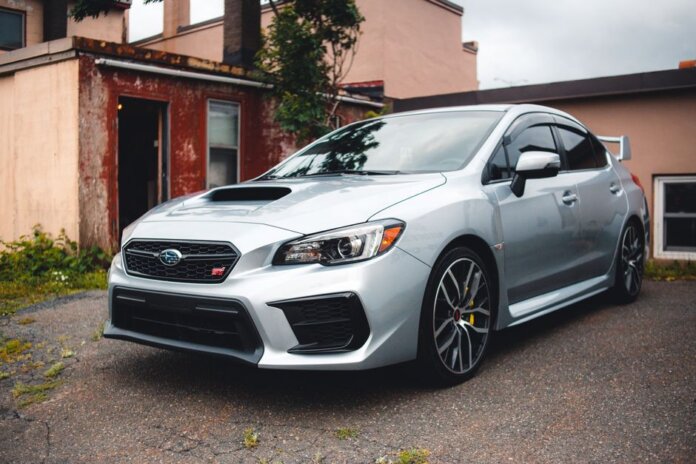 Silver Subaru WRX STI parked in a residential driveway with rustic backdrop. Silver Subaru WRX STI parked in a residential driveway with rustic backdrop.