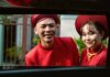 Smiling couple in traditional red Ao Dai attire celebrating in Ho Chi Minh City.