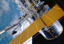 Десятилетие космических открытий: карта тёмной материи Вселенной Spacecraft with solar panels orbiting Earth, showcasing modern astronautic technology.