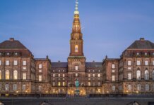 Stunning evening view of Christiansborg Palace with its illuminated spire in Copenhagen, Denmark.