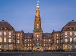 Stunning evening view of Christiansborg Palace with its illuminated spire in Copenhagen, Denmark.