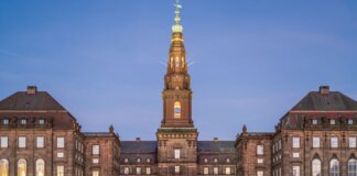 Stunning evening view of Christiansborg Palace with its illuminated spire in Copenhagen, Denmark.