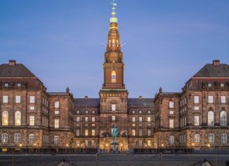 Stunning evening view of Christiansborg Palace with its illuminated spire in Copenhagen, Denmark.