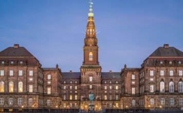 Stunning evening view of Christiansborg Palace with its illuminated spire in Copenhagen, Denmark.
