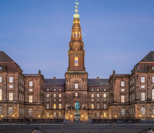 Stunning evening view of Christiansborg Palace with its illuminated spire in Copenhagen, Denmark.