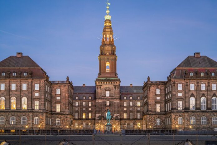 Stunning evening view of Christiansborg Palace with its illuminated spire in Copenhagen, Denmark. Stunning evening view of Christiansborg Palace with its illuminated spire in Copenhagen, Denmark.
