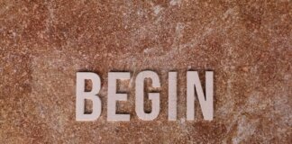 Text 'BEGIN' on a textured stone background, symbolizing a fresh start.