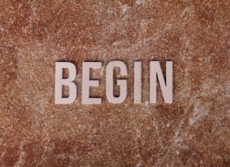 Text 'BEGIN' on a textured stone background, symbolizing a fresh start.