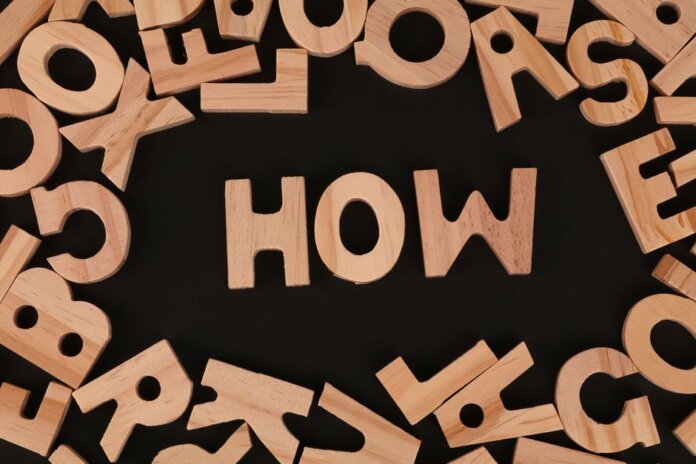 Top view of scattered wooden letters with 'HOW' centered on a dark surface, promoting inquiry. Top view of scattered wooden letters with 'HOW' centered on a dark surface, promoting inquiry.