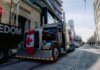 Truck convoy with Canadian flag during protest in downtown street. Demonstration for freedom movement.