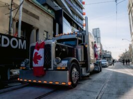 Truck convoy with Canadian flag during protest in downtown street. Demonstration for freedom movement.