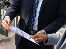 Two business professionals discussing and exchanging documents outdoors in Piura, Peru.