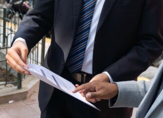Two business professionals discussing and exchanging documents outdoors in Piura, Peru.