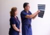 Two healthcare professionals in scrubs examining a medical x-ray image, discussing diagnosis.