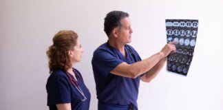 Two healthcare professionals in scrubs examining a medical x-ray image, discussing diagnosis.
