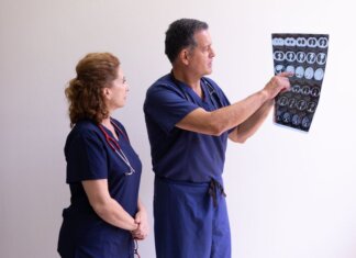 Two healthcare professionals in scrubs examining a medical x-ray image, discussing diagnosis.