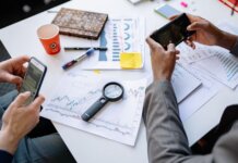 Западный университет помогает Goodwill перерабатывать отходы Two professionals analyzing data and graphs with smartphones on a white table.