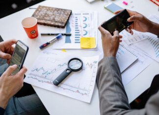 Западный университет помогает Goodwill перерабатывать отходы Two professionals analyzing data and graphs with smartphones on a white table.