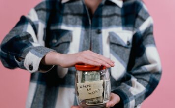 Консерваторы требуют от Карни представить план по снятию пошлин США Woman in plaid shirt holds money jar with travel goals in mind.