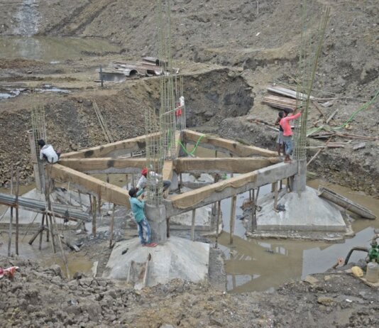 Workers constructing a building foundation with rebar and wooden supports outdoors.
