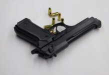 A black pistol with scattered bullets on a white surface, showcasing weaponry and security themes.