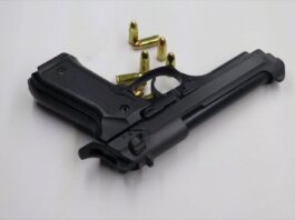 A black pistol with scattered bullets on a white surface, showcasing weaponry and security themes.
