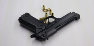 A black pistol with scattered bullets on a white surface, showcasing weaponry and security themes.