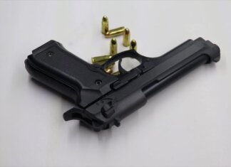 A black pistol with scattered bullets on a white surface, showcasing weaponry and security themes.
