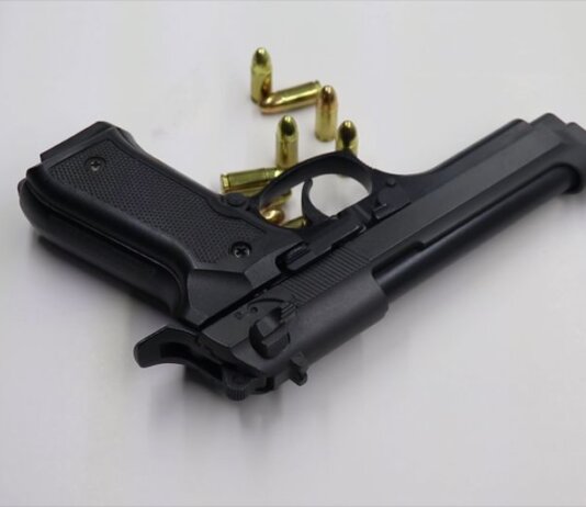 A black pistol with scattered bullets on a white surface, showcasing weaponry and security themes.