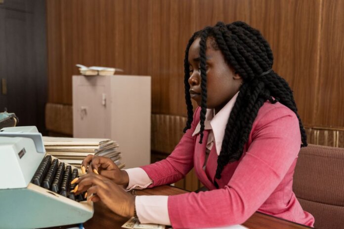 A businesswoman typing in a vintage office setting, highlighting the retro style and classic workplace ambiance. A businesswoman typing in a vintage office setting, highlighting the retro style and classic workplace ambiance.