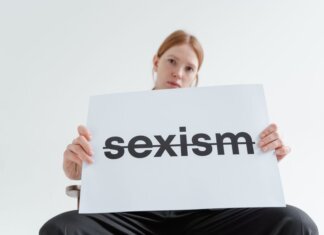 Пьер Пуальевр: заявление лидера консерваторов ко Дню эмансипации A caucasian woman confidently holds a sign addressing sexism in a bright studio setting.