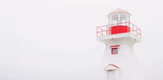 HMCS Charlottetown вернулся в Галифакс после миссии в Индо-Тихоокеанском регионе A charming red and white lighthouse stands on a tranquil seaside landscape.