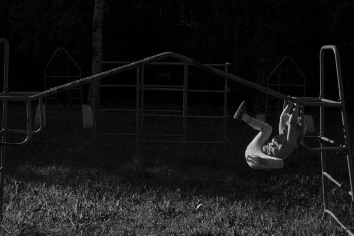 A child gracefully swings on monkey bars at a playground, captured in a black and white image. A child gracefully swings on monkey bars at a playground, captured in a black and white image.