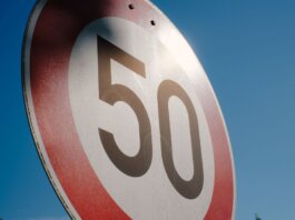 A close-up of a speed limit sign displaying 50 against a clear blue sky backdrop.