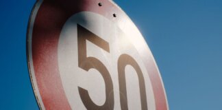 A close-up of a speed limit sign displaying 50 against a clear blue sky backdrop.