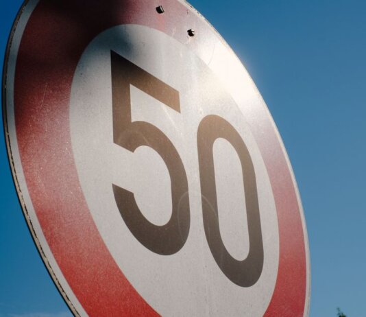 A close-up of a speed limit sign displaying 50 against a clear blue sky backdrop.