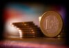 A close-up shot of stacked euro coins with a blurred colorful background, representing financial concepts.