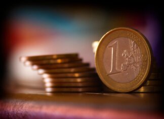 A close-up shot of stacked euro coins with a blurred colorful background, representing financial concepts.
