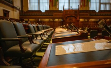 A detailed view of an empty legislative chamber with rows of desks and microphones, evoking governance.