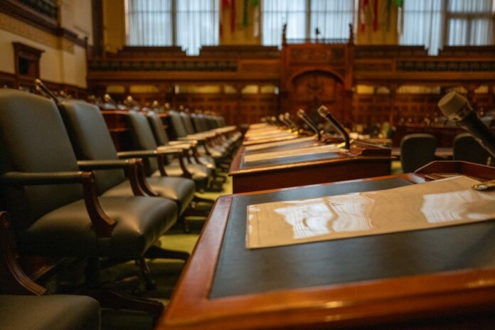 A detailed view of an empty legislative chamber with rows of desks and microphones, evoking governance. A detailed view of an empty legislative chamber with rows of desks and microphones, evoking governance.