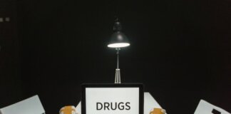 A dimly lit room with a sign displaying 'DRUGS' surrounded by money and illegal substances.