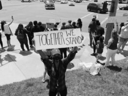A diverse group of activists protesting peacefully with signs on a street corner.